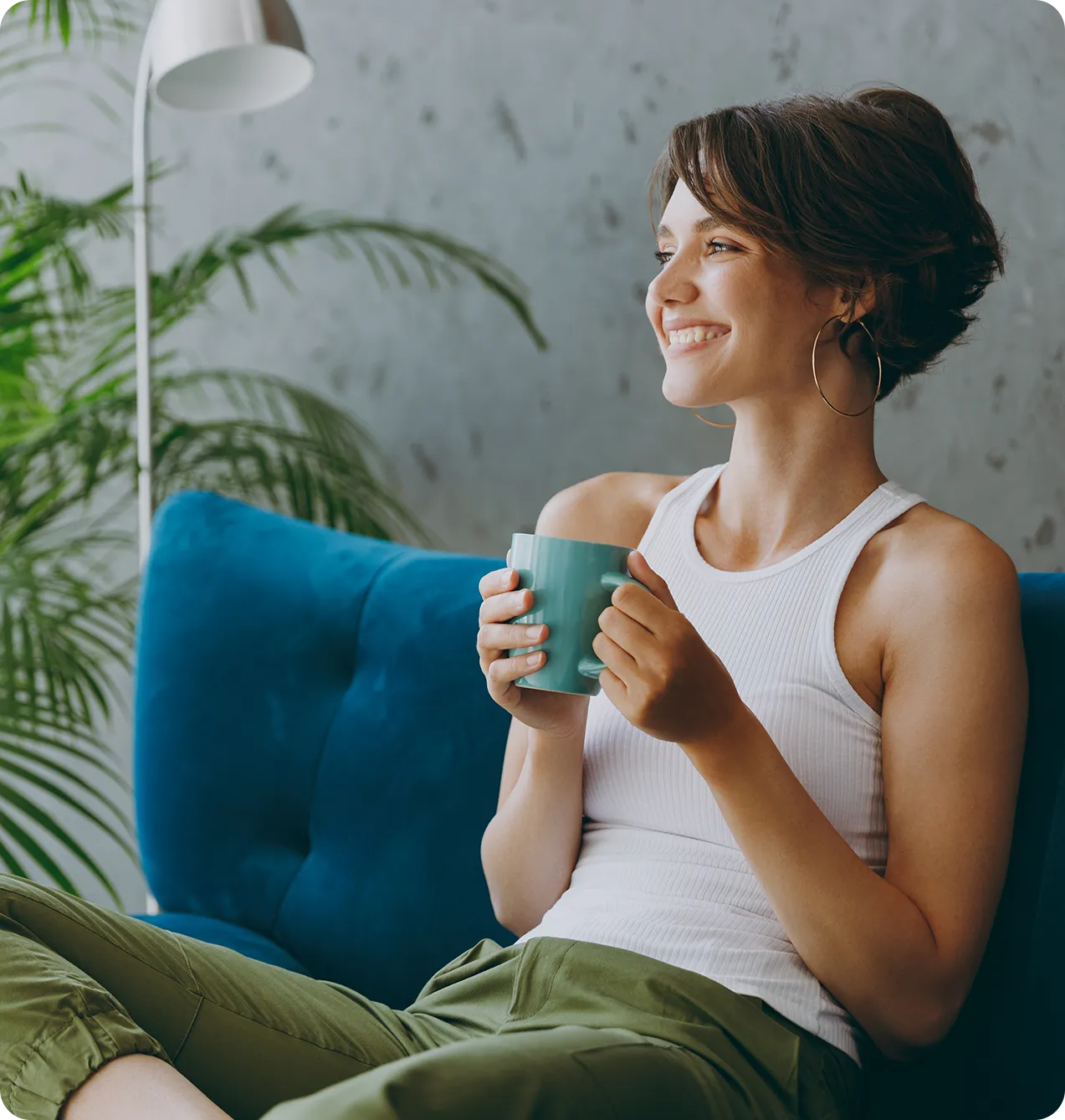 young woman on teal couch holding cup of coffee